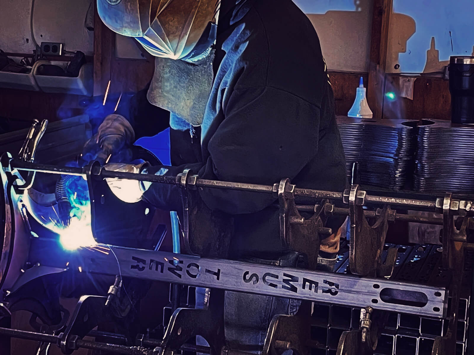 A welder welds on a Remus Tower beacon extension with the words Remus Tower cut out of the side.